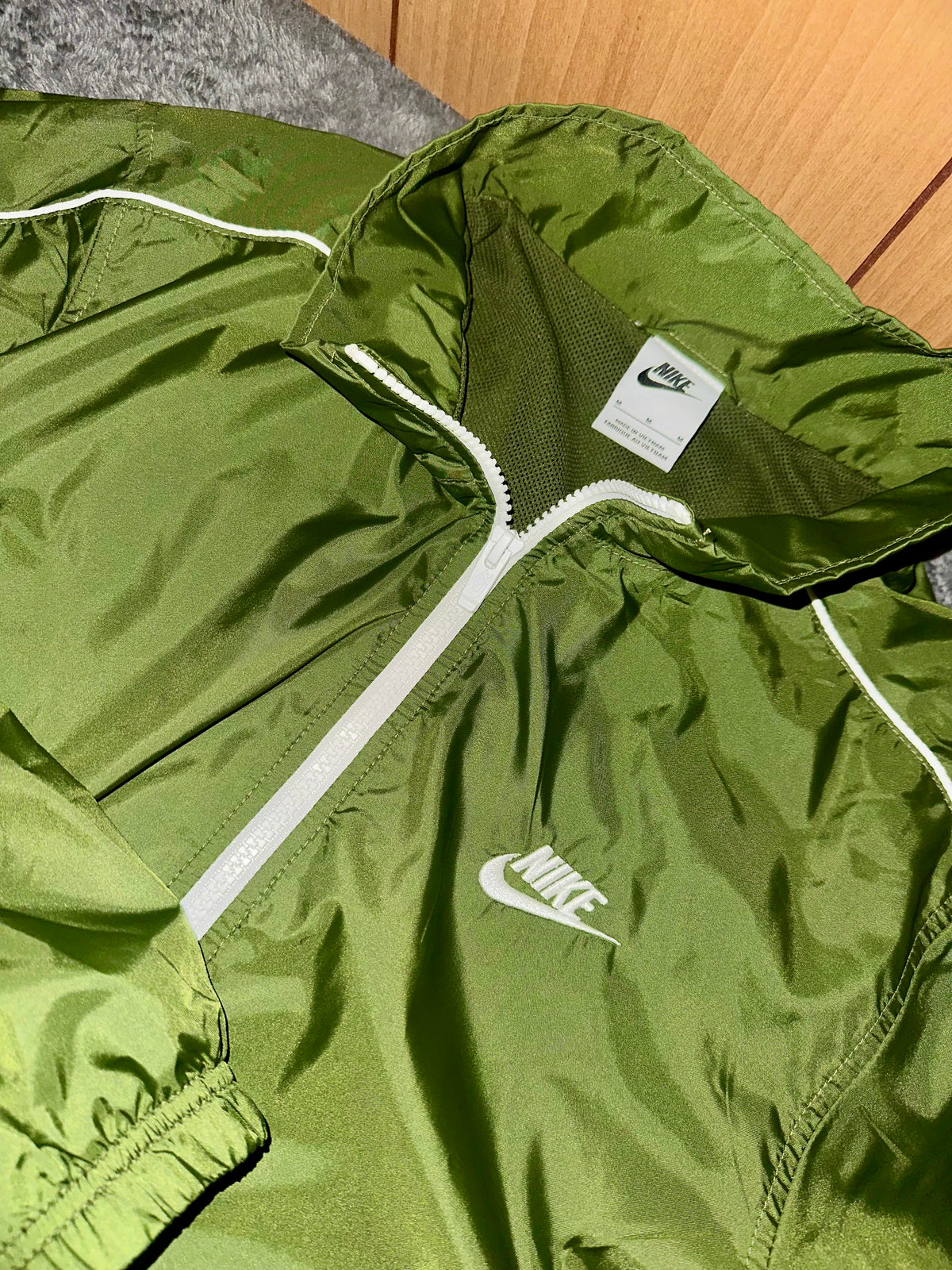 Dettaglio del collo, della zip e del logo Nike sulla giacca verde oliva