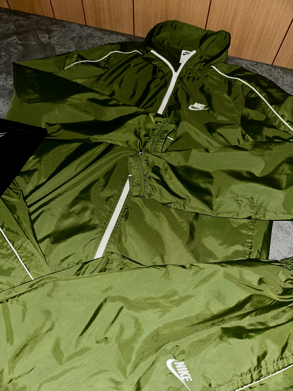 Giacca e pantaloni Nike verde oliva, dettaglio dei loghi bianchi